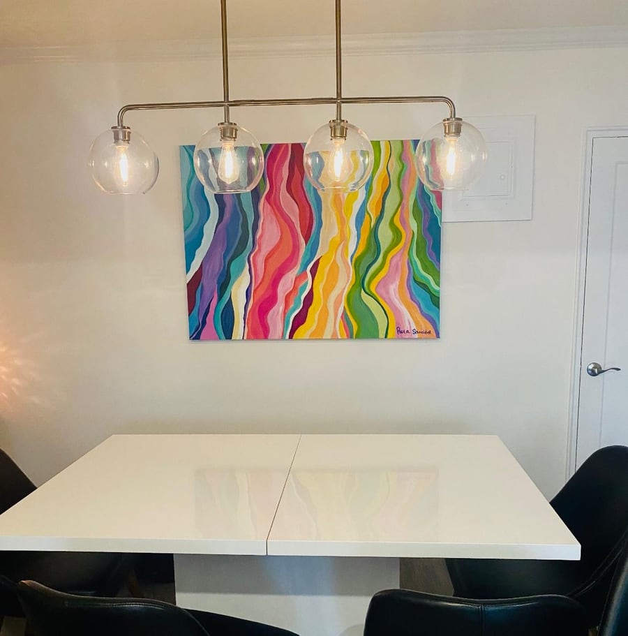 A finished rainbow-wave canvas by Paula hanging in a customer's dining room